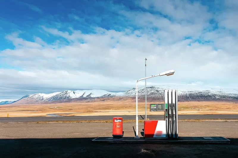 Fuel pumps standing alone in open country below mountains