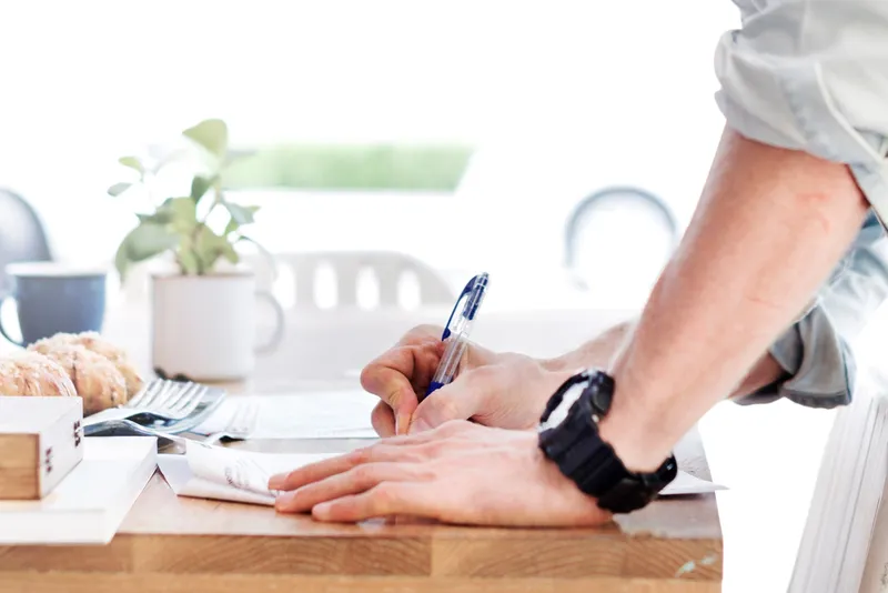 Hands signing paperwork on a desk