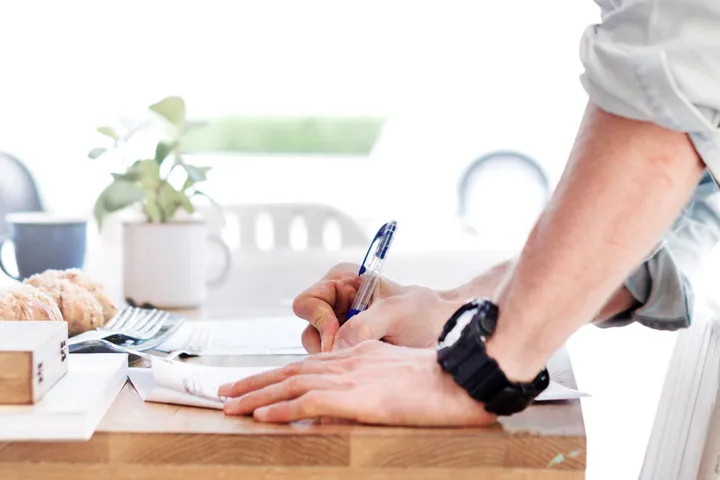 Hands signing paperwork on a desk