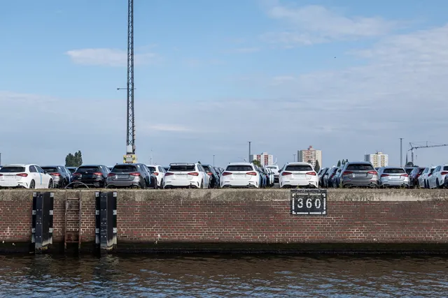 New cars lined up on a port quay by the water