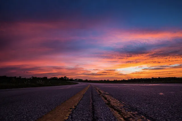 Empty highway under a vivid sunset sky