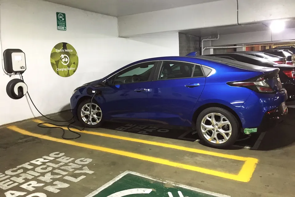 Electric car plugged into a wall charger in a parking garage