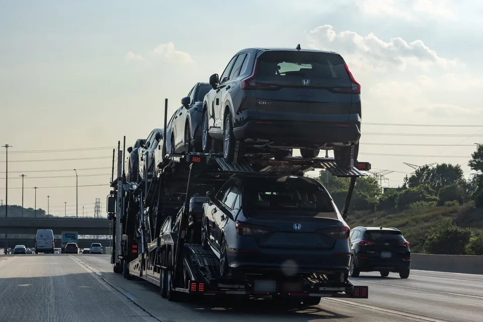 Open car carrier loaded with SUVs on a multi-lane highway