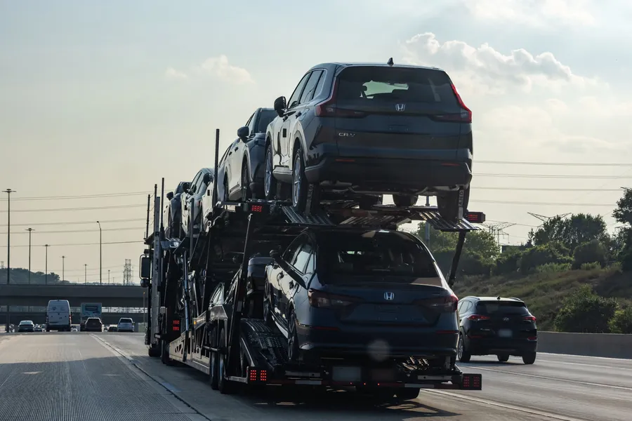 Open car carrier loaded with SUVs on a multi-lane highway