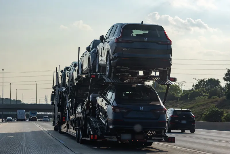 Open car carrier loaded with SUVs on a multi-lane highway