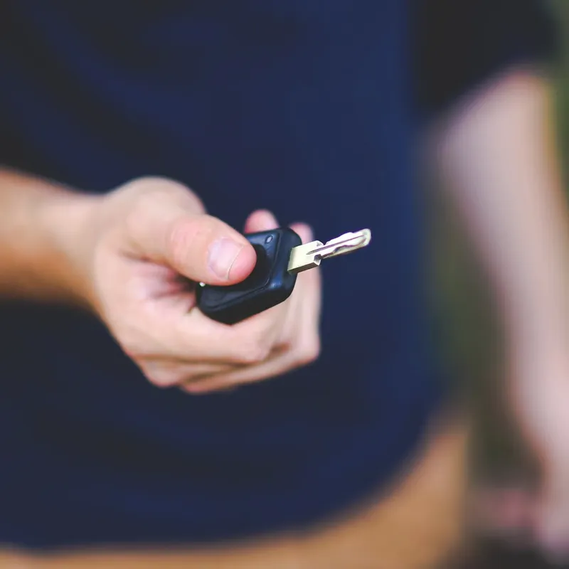 Hand holding out a car key