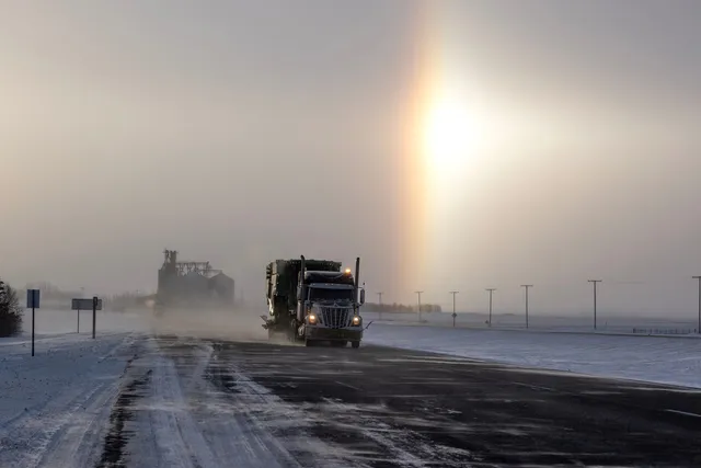 Semi truck on a snowy, windswept prairie highway